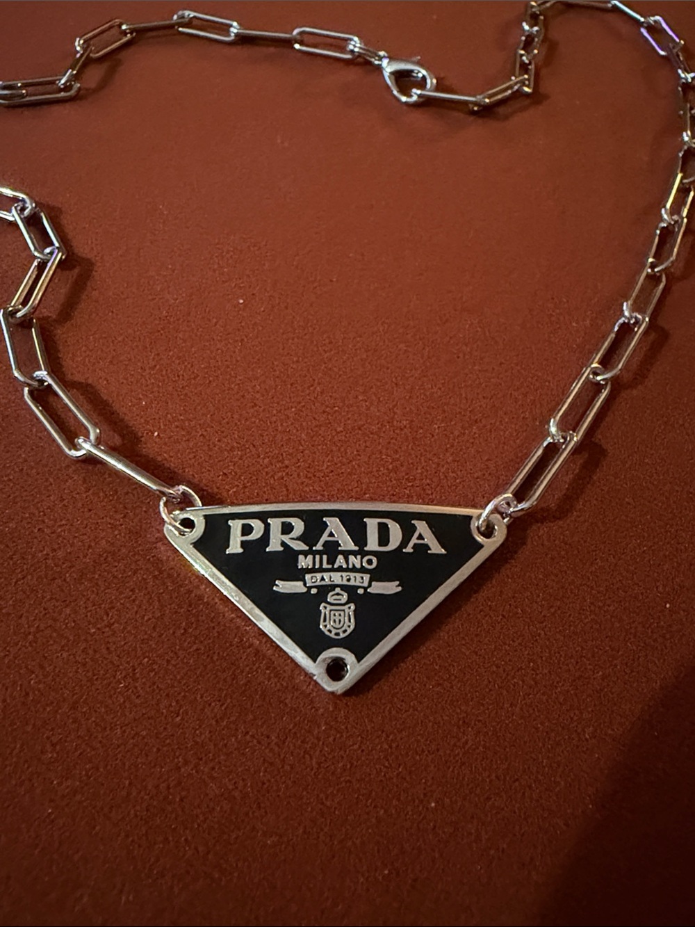 An Adjustable Silver Chain Necklace with Black Triangle Logo Pendant